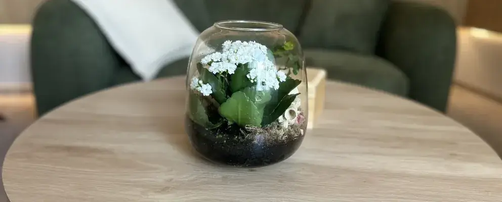 Detal gabinetu: stolik z terrarium i zielona sofa